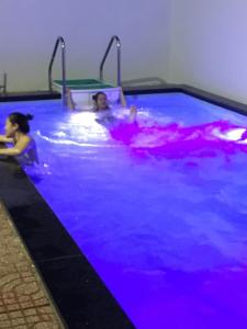 two women swimming in a pool with purple lights at Dang Duy Hotel in Lagi +24 photos