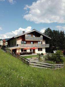 a large house on a hill with a green field at Ferienhaus Sonnhof am Walchsee in Kössen