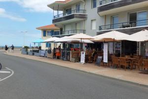 a cafe with tables and umbrellas on the side of a building at Beach Front Apartment Eljocri in Capbreton