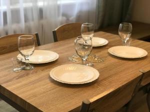 een houten tafel met borden en wijnglazen erop bij Golden Apartament Proletariacka in Białystok