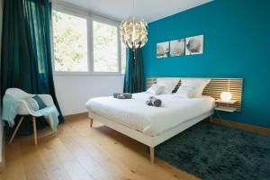a blue bedroom with a bed and a chandelier at Le Célestay in Villeurbanne