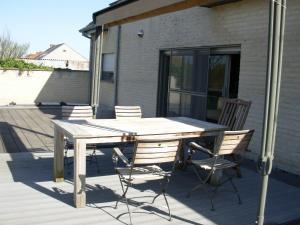 una mesa de madera y sillas en una terraza en B&B Appelkers II en Kortessem