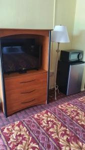 a room with a bed with a dresser and a television at Palms Inn in Dania Beach