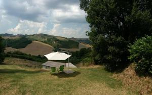 um guarda-chuva branco e duas cadeiras num campo em B&B Cà Giovanni Country Resort em Urbino