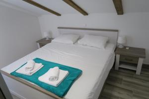 a white bed with two towels on top of it at Family Apartment in Baška