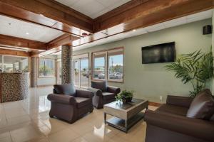 a living room with leather furniture and a flat screen tv at Baymont by Wyndham Panama City Beach in Panama City Beach