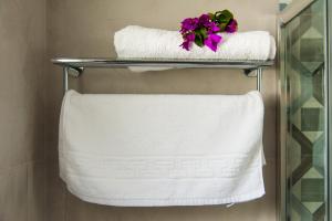 a towel rack with white towels and purple flowers at Nostos Studios in Aegiali