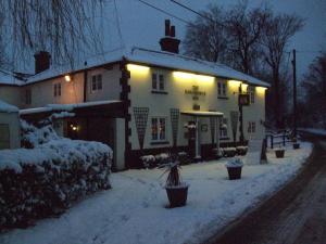 a inn in the snow with lights on it at The Winchfield Inn in Winchfield