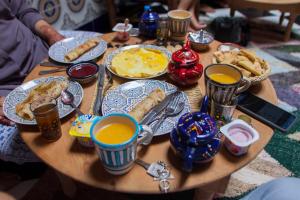 una mesa de madera cubierta con platos de comida y bebida en Mosaic Hostel, en Marrakech