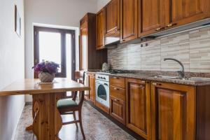 eine Küche mit Holzschränken, einem Tisch und einer Spüle in der Unterkunft Casa Vacanze Rizzo in Santa Maria di Castellabate