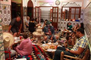 a group of people sitting at tables in a restaurant at Mosaic Hostel in Marrakesh