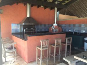 a kitchen with a bar with stools and a stove at Juquehy - Condomínio de Frente para o Mar - Piscina Aquecida - Quadra de Tenis in Juquei