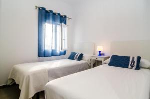 ビリャホヨサにあるThe Sailor Houseの白い部屋のベッド2台(青いカーテン付)