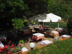 un restaurant en plein air avec des tables et un parasol dans l'établissement Hotel Bayle, à Belcaire