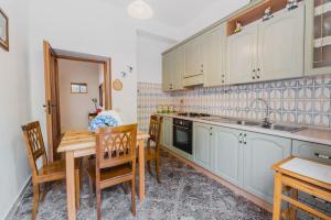eine Küche mit weißen Schränken und einem Tisch und Stühlen in der Unterkunft Casa Vacanze Rizzo in Santa Maria di Castellabate