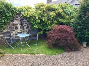 uma mesa e cadeiras num jardim com arbustos em The Cottage em Belford