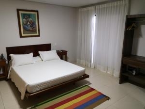 sypialnia z białym łóżkiem i kolorowym dywanem w obiekcie Hotel La Dolce Vita w mieście Ilhéus