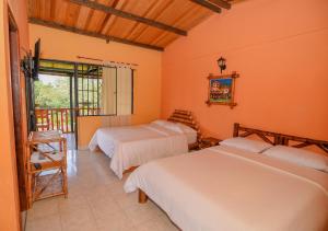 2 Betten in einem Zimmer mit orangefarbenen Wänden in der Unterkunft Hotel Alto de los Andaquies in San Agustín