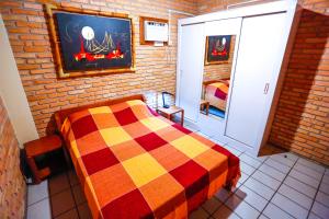 1 dormitorio con 1 cama colorida en una pared de ladrillo en Cabanas Jurerê, en Florianópolis