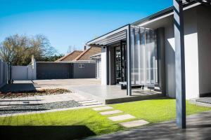 a modern house with glass doors and a yard at @Greys Guesthouse in Bloemfontein