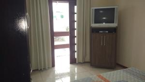 1 dormitorio con TV en un tocador con puerta en Casa de Praia em Meia Praia, en Itapema