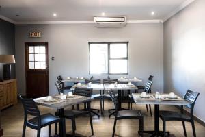 ein Restaurant mit Tischen und Stühlen in einem Zimmer in der Unterkunft @Greys Guesthouse in Bloemfontein