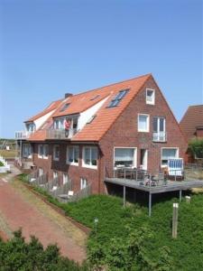 ein großes rotes Backsteinhaus mit einer Veranda und einer Terrasse in der Unterkunft Haus Kap Horn in Juist