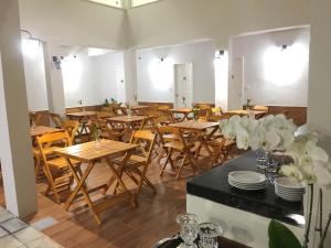 a restaurant with wooden tables and chairs and flowers at Hotel Portal do Descobrimento in Porto Seguro