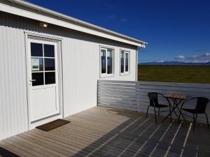 a white building with a table and chairs on a deck at Beindalsholt in Hella
