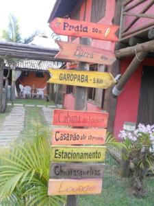 um poste com muitas placas em frente a um edifício em Cabanas Aconchegantes próximas ao mar em Garopaba