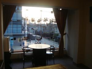 Habitación con mesa, sillas y ventana grande. en Hostal Bond, en Lima