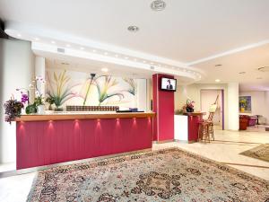 a lobby with a red wall and a counter at Hotel Sporting in San Benedetto del Tronto