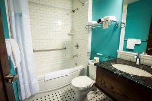 a bathroom with a toilet, sink, tub and shower at Hume Hotel & Spa in Nelson