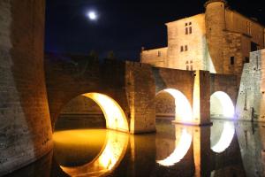 a view of a bridge at night with a castle at Studio 237 Port Camargue, Piscine, Climatisation, 2 personnes in Le Grau-du-Roi