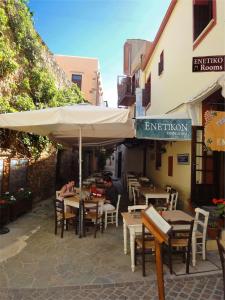 two people sitting at a restaurant under an umbrella at Enetiko Rooms in Chania Town