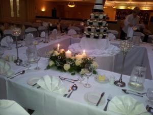 uma mesa com mesas brancas com velas e um bolo de casamento em Blarney Castle Hotel em Blarney