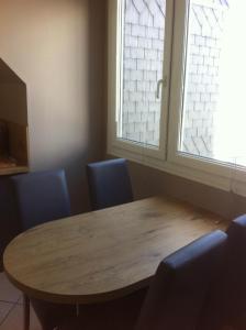 een houten tafel en stoelen in een kamer met 2 ramen bij Chez Fifille appartement dans Honfleur parking privé in Honfleur
