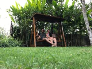 
a wooden bench sitting in the middle of a grassy field at El Homestay Bali in Nusa Dua
