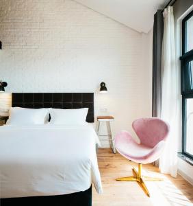 um quarto com uma cama branca e uma cadeira rosa em Cendre Hotel (Lingering Garden and Tiger Hill) em Suzhou