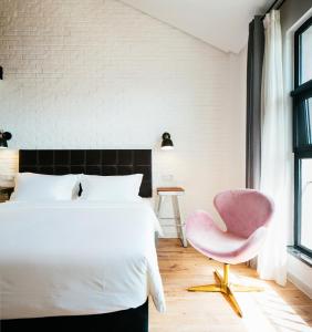 een slaapkamer met een wit bed en een roze stoel bij Cendre Hotel (Lingering Garden and Tiger Hill) in Suzhou