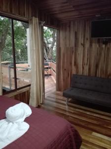 a bedroom with a bed and a couch and a balcony at The Green Tree Lodge in Monteverde Costa Rica