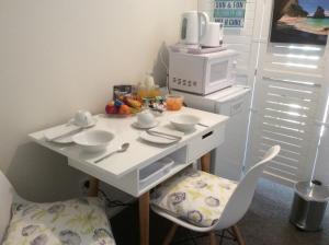 a kitchen with a white table and a microwave at Albert Mews B and B in Whitianga
