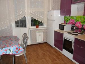 ニジネヴァルトフスクにあるApartment on Ryabinovyy Bul'var 11のキッチン(紫色のキャビネット、テーブル、電子レンジ付)