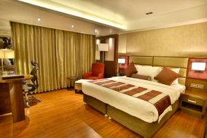 a hotel room with a large bed and a desk at Regenta Central the Crystal Kanpur, in Kānpur
