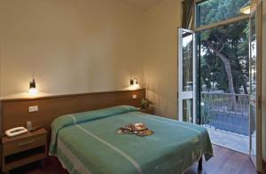 a bedroom with a green bed and a large window at Hotel Firenze in Viareggio