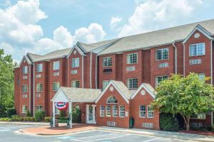 a large red brick building with a tree at Microtel Inn & Suites by Wyndham Stockbridge/Atlanta I-75 in Stockbridge