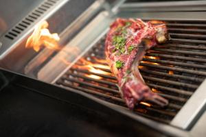 un pedazo de carne está cocinando en una parrilla en Hotel La Santa, en Santa-Reparata-di-Balagna