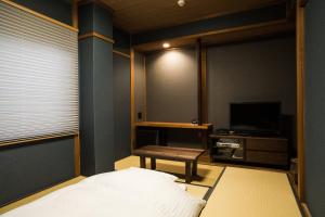 a bedroom with a bed and a table and a television at Hotel Daiei Masuda in Masuda