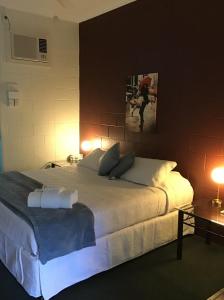 a bedroom with a large white bed with two lamps at Harbour Lodge Motel in Gladstone