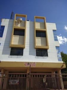 un bâtiment blanc avec des fenêtres jaunes et une clôture dans l'établissement Balaji Lodging, à Pandharpur